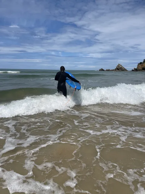 Kam Nganssoh Gildas entrant dans les vagues avec une planche de surf