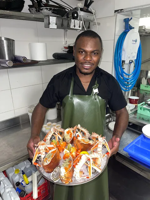Kam Nganssoh Gildas en cuisine de restaurant, presentant un plateau de fruits de mer
