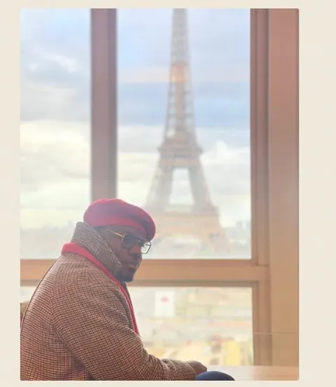Kam Nganssoh Gildas assis devant la Tour Eiffel