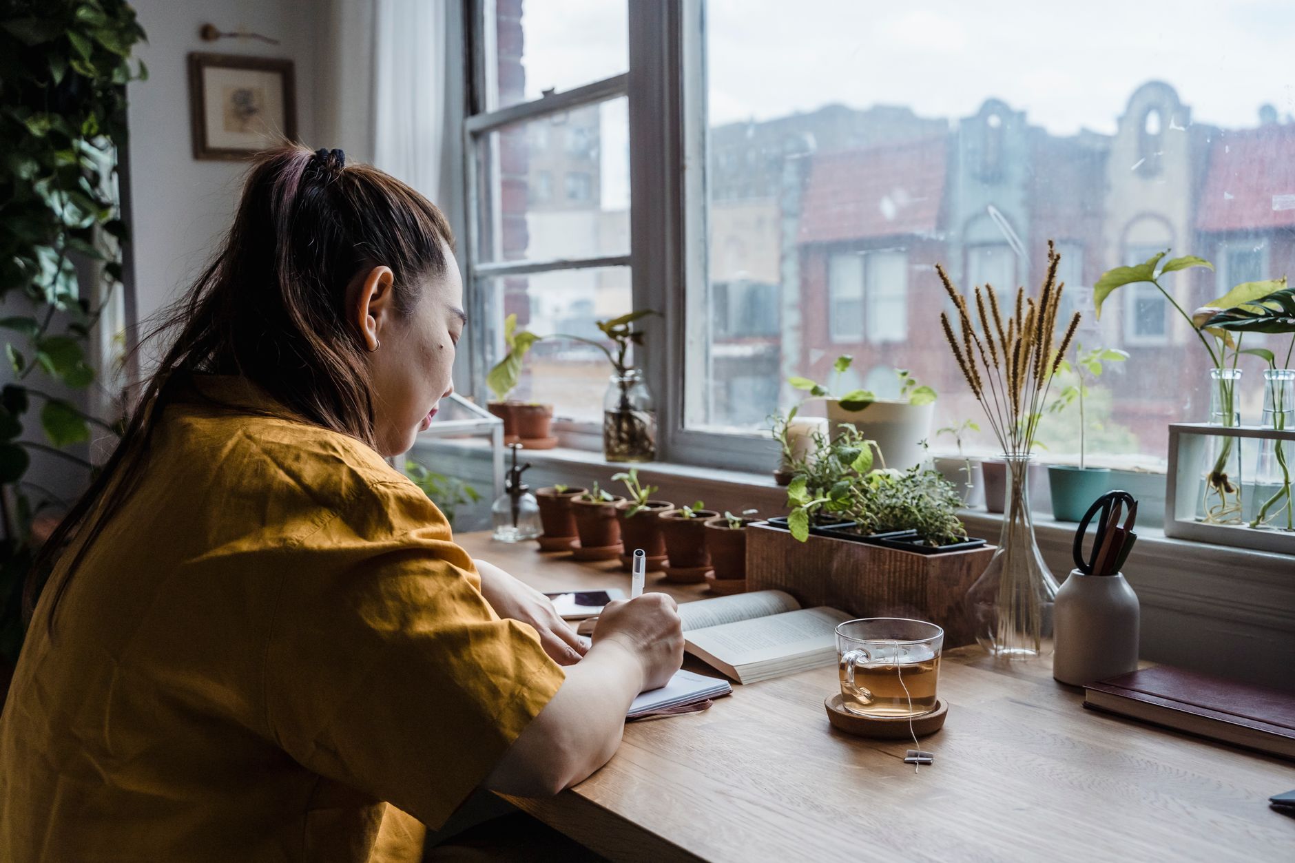 Une personne écrivant à un bureau, symbole de la solitude créatrice et de la réflexion introspective