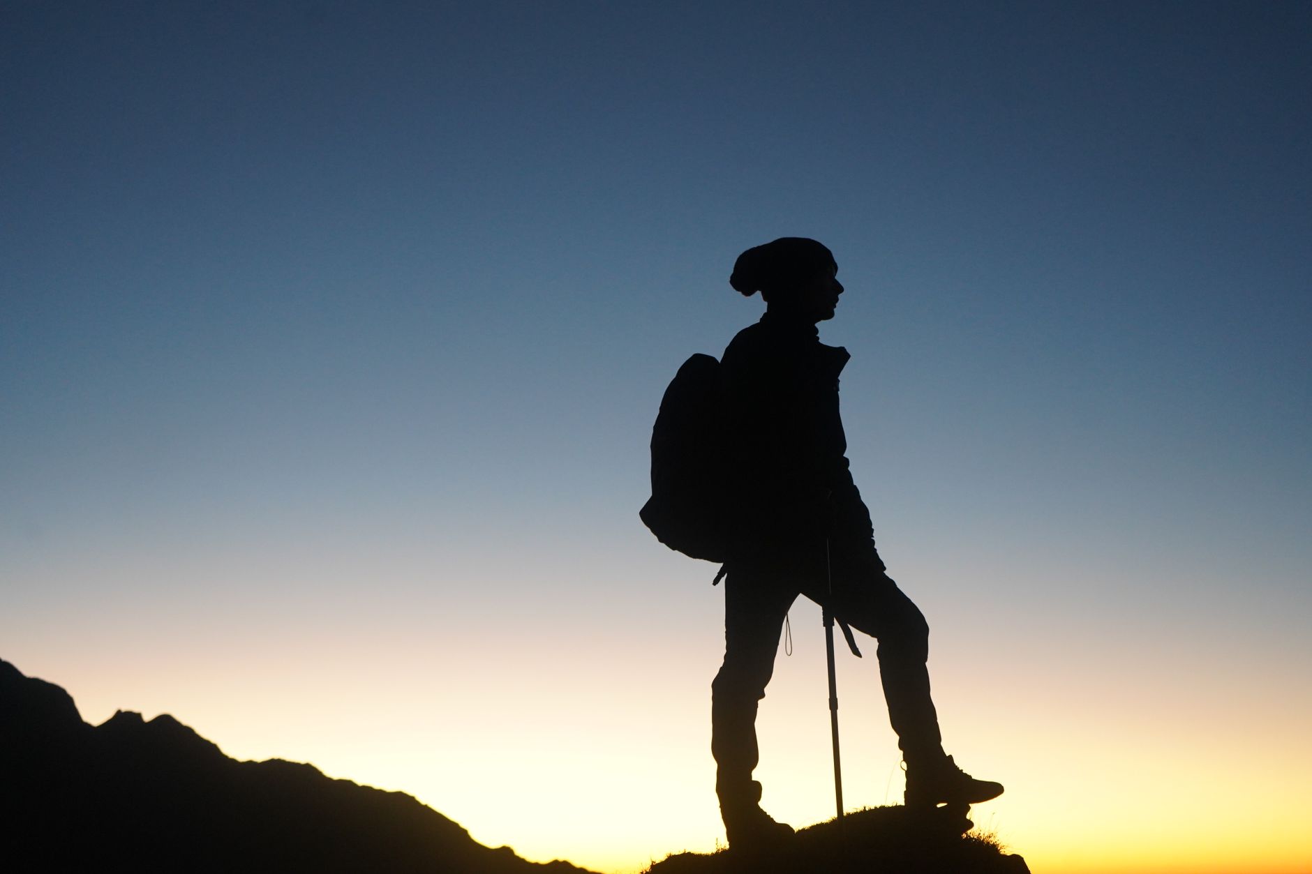 Personne escaladant une montagne au lever du soleil, symbolisant l'ascension et l'espoir